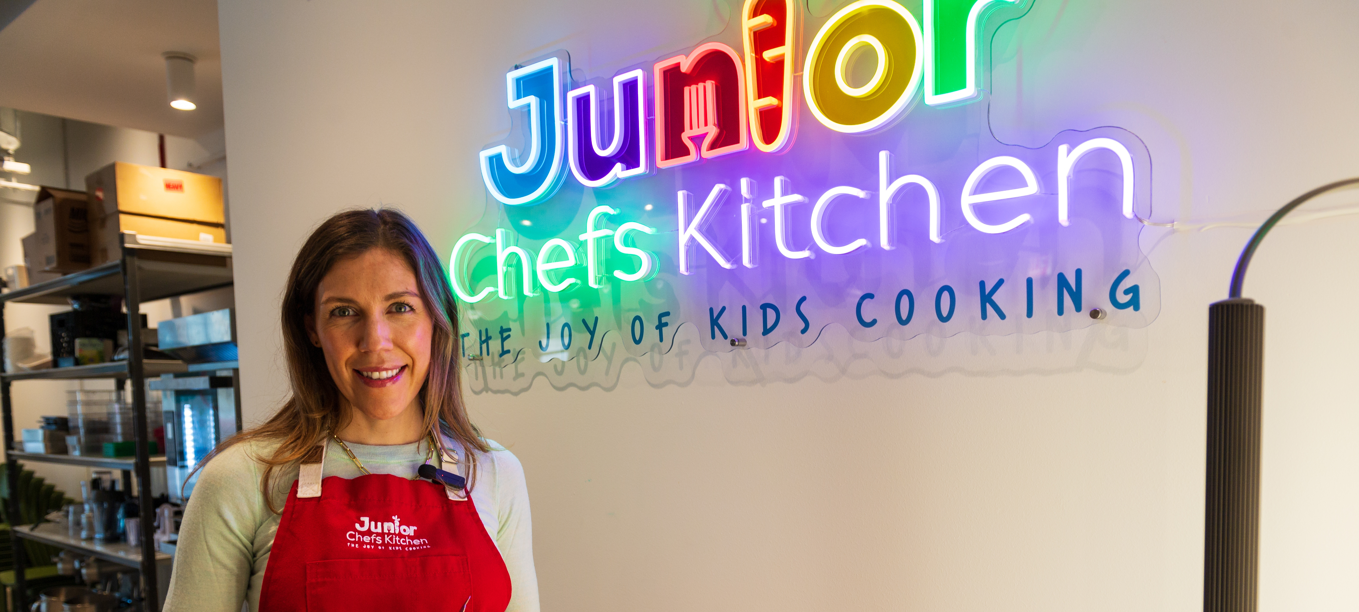 Owner Niki Cordell with sign for Junior Chefs Kitchen 